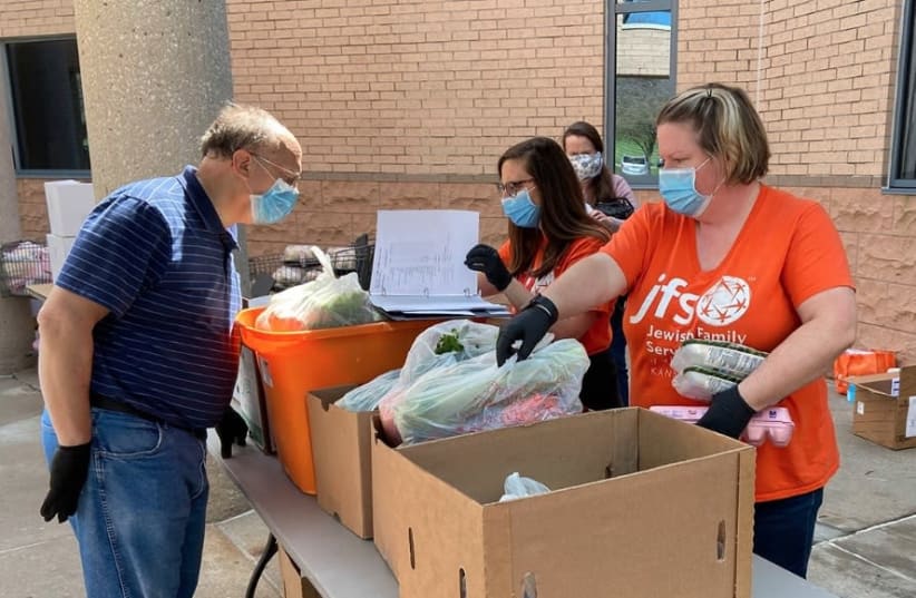 Food pantry volunteers work outside at the Jewish Federation of Kansas City amid the adoption of new pandemic-era health-and-safety protocols by Jewish institutions around the country. (photo credit: COURTESY OF JFGKC/JTA)