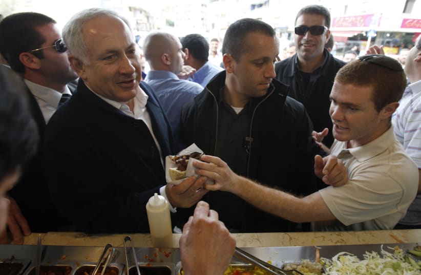 Israel's Likud party leader Benjamin Netanyahu (L) buys a falafel sandwich while campaigning in the northern city of Tiberias February 8, 2009 (photo credit: REUTERS/BAZ RATNER)