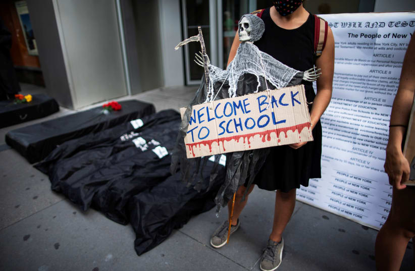 Fake morgue bags and coffins are seen near the entrance of United Federation of Teachers as symbol of students dead by the coronavirus disease (COVID-19) as people take part in a march and rally during the National Day of Resistance to schools re-opening in New York City, U.S., August 3, 2020. (photo credit: REUTERS)