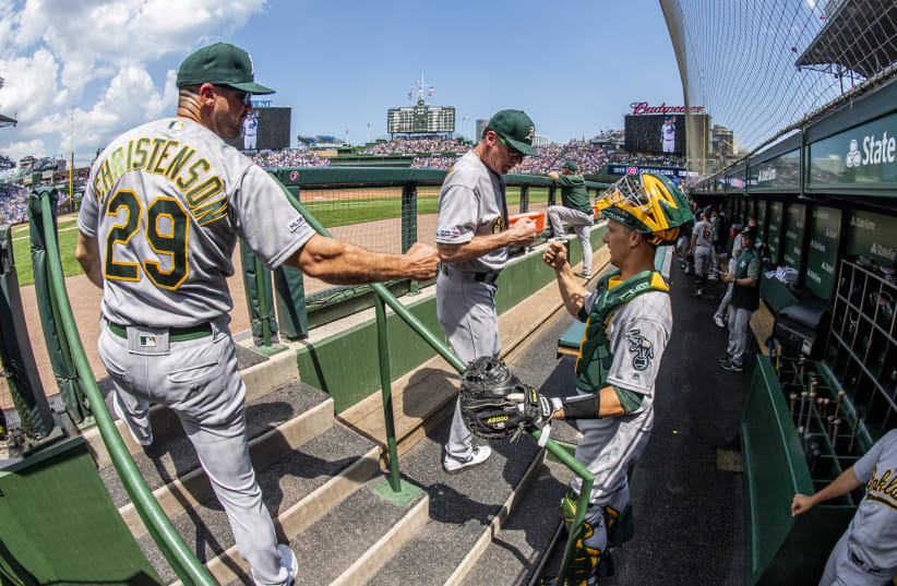 Aug 7, 2019; Chicago, IL, USA; Oakland Athletics manager Bob Melvin (center), and bench coach Ryan Christenson (left), fist bump catcher Dustin Garneau (right) prior to a game against the Chicago Cubs at Wrigley Field. Mandatory Credit: Patrick Gorski-USA TODAY Sports (photo credit: REUTERS)