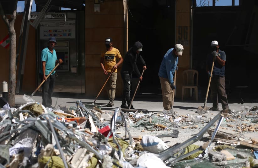 People clean debris from the street following Tuesday's blast in Beirut's port area, Lebanon August 9, 2020. (photo credit: HANNAH MCKAY/ REUTERS)