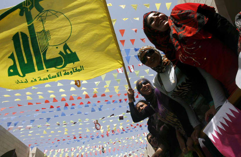 Residents hold Hezbollah and Qatari flags during the visit of the Emir of Qatar Sheikh Hamad bin Khalifa al-Thani to the village of Bint Jbeil, southern Lebanon July 31, 2010. (photo credit: REUTERS)