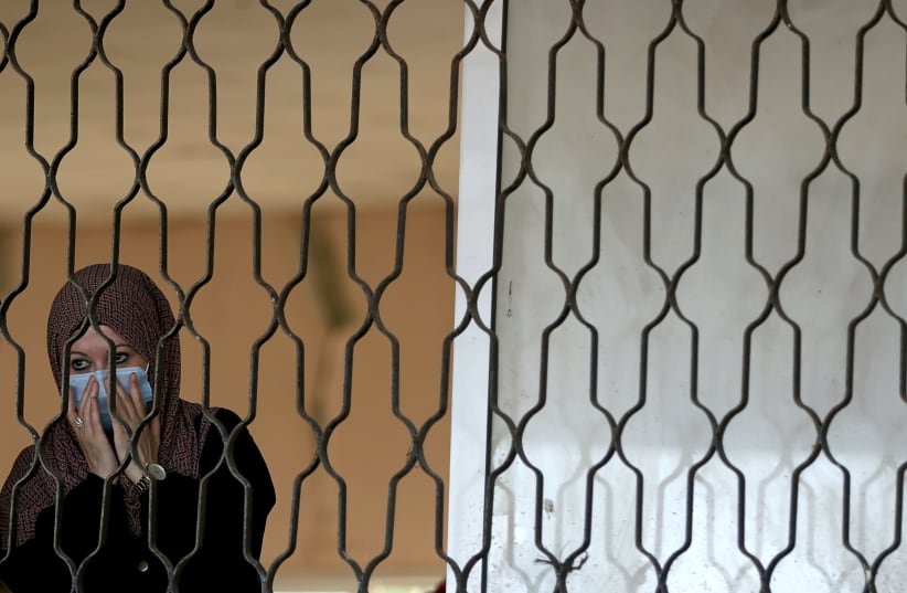 A Palestinian woman waits before leaving Rafah border crossing with Egypt, which was reopened for the first time since it was closed in March over Covid-19 concerns, in the southern Gaza strip August 11, 2020. (photo credit: IBRAHEEM ABU MUSTAFA / REUTERS)