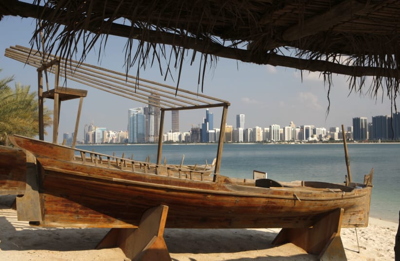 A view of the Abu Dhabi skyline is seen past a boat on a beach (photo credit: AHMED JADALLAH/REUTERS)
