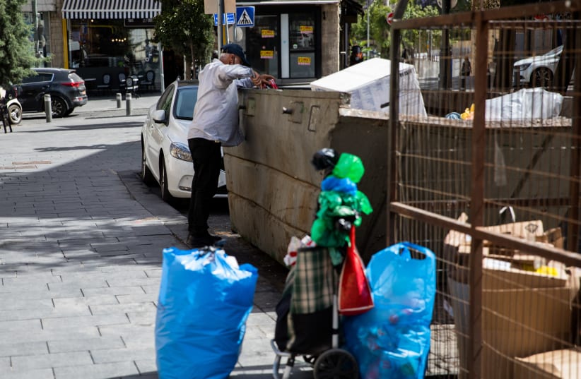 A man searches through trash in the city center of Jerusalem, June 02 2020. (photo credit: NATI SHOHAT/FLASH90)