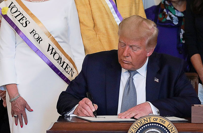 U.S. President Donald Trump signs a proclamation marking the 100th anniversary of the ratification of the 19th Amendment of the U.S. Constitution during a ceremony in the Blue Room at the White House in Washington, U.S., August 18, 2020 (photo credit: REUTERS/CARLOS BARRIA)