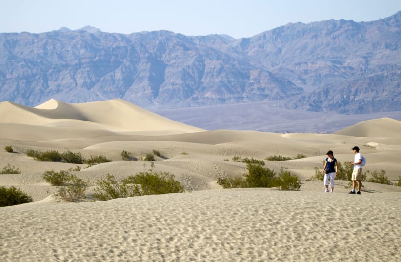 Italian tourists walk in the Mesquite Dunes during heat wave in Death Valley National Park, California (photo credit: STEVE MARCUS/REUTERS)