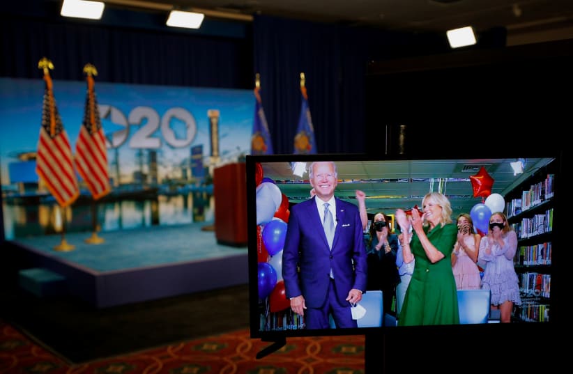 Joe Biden is seen in a video feed from Delaware being applauded by his wife Jill and his grandchildren after winning the votes to become the Democratic Party's 2020 nominee for president (photo credit: BRIAN SNYDER/REUTERS)