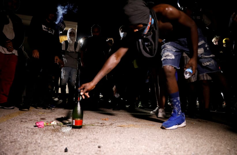A bottle of alcohol and flowers are left in tribute to the victims of a shooting during Tuesday night's protests, at the site of the incident, during a protest following the police shooting of Jacob Blake, a Black man, in Kenosha, Wisconsin, U.S. August 26, 2020. (photo credit: BRENDAN MCDERMID/REUTERS)