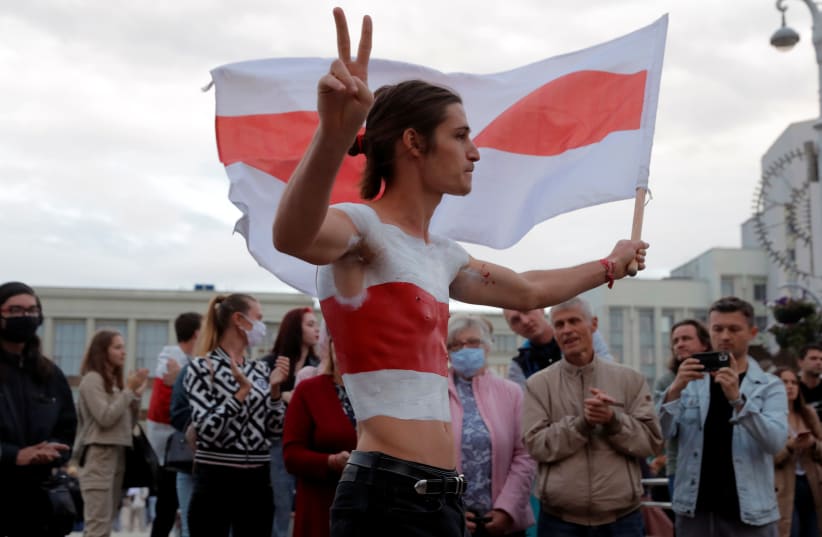 A person waving a historical white-red-white flag of Belarus flashes a victory sign as people take part in a rally to protest against presidential election results, at the Independence Square in Minsk, Belarus, August 26, 2020 (photo credit: VASILY FEDOSENKO / REUTERS)