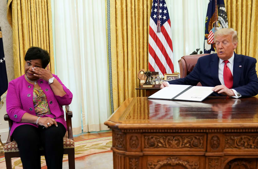 Alice Johnson, who received a life sentence for a first-time drug offense, receives a pardon from U.S. President Donald Trump in the Oval Office of the White House in Washington, U.S., August 28, 2020. (photo credit: KEVIN LAMARQUE/REUTERS)
