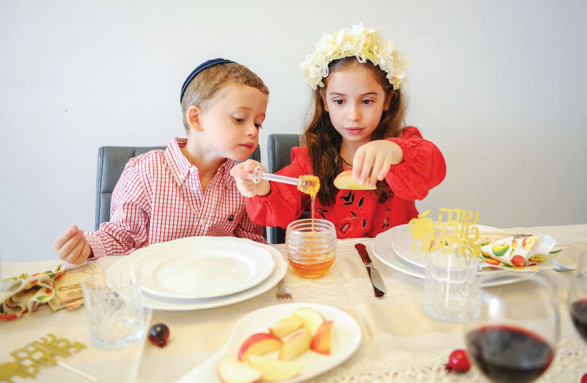 DIPPING APPLES in honey for a sweet new year (photo credit: MENDY HECHTMAN/FLASH90)