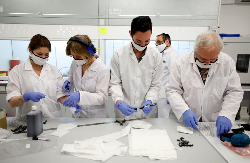 Employees of Israel's Sonovia Ltd, makers of washable and reusable antiviral masks, which the company says can help stop the spread of the coronavirus disease (COVID-19), work at their laboratory in Ramat Gan, Israel May 17, 2020 (photo credit: REUTERS/AMIR COHEN)