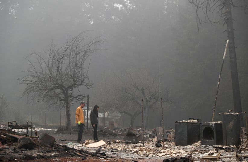 Dane Valentine, 28, and his wife Hansel, 24, inspect the remains of the burnt down property of their relatives, Estacada, Oregon, US, September 13, 2020  (photo credit: SHANNON STAPLETON / REUTERS)