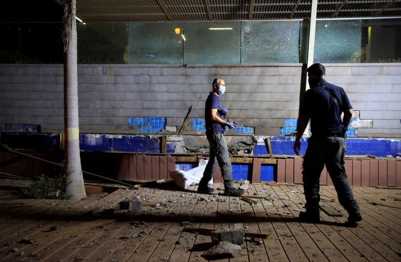 Israeli security personnel check the scene of an explosion following a rocket attack fired from Gaza in Ashdod (photo credit: AMIR COHEN/REUTERS)