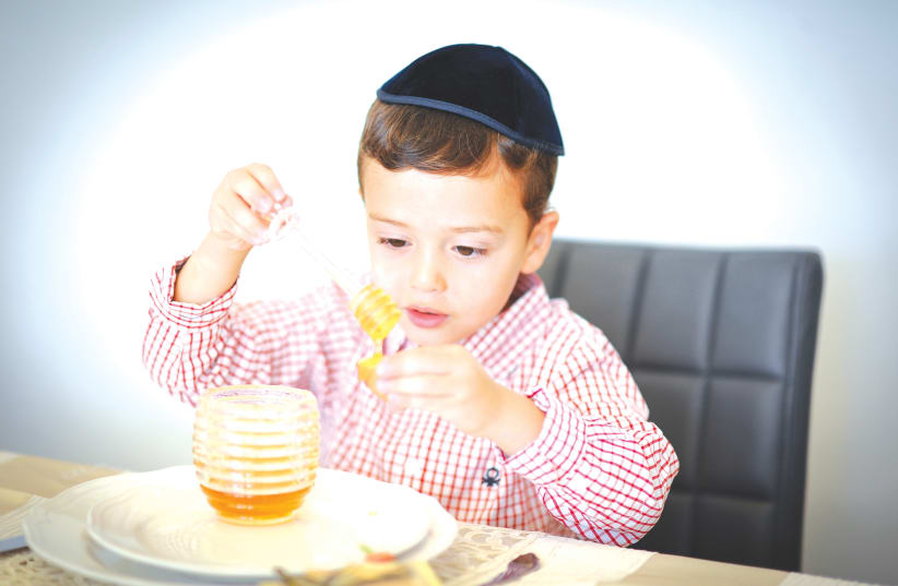 A BOY prepares to eat an apple with honey, as is traditional on Rosh Hashanah.  (photo credit: MENDY HECHTMAN/FLASH90)