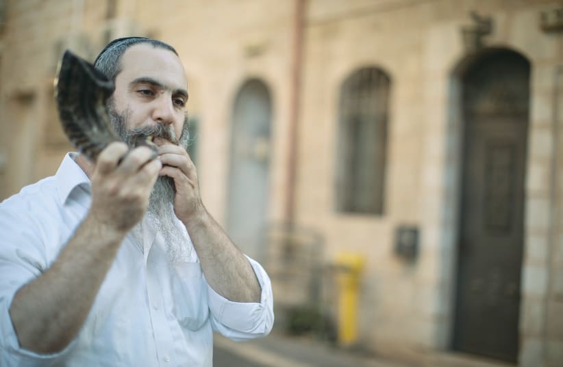 AN ULTRA-ORTHODOX man watches protesters march across Jerusalem’s ‘Bridge of Strings’ in August.  (photo credit: REUTERS)