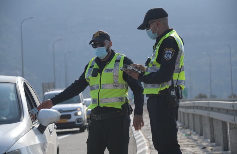 Police check the ID of a driver, at a checkpoint put in place during Israel's second lockdown, September 2020. (photo credit: AVSHALOM SASSONI/ MAARIV)