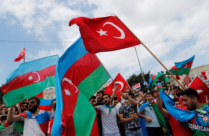 Azeri men living in Turkey wave flags of Turkey and Azerbaijan during a protest following clashes between Azerbaijan and Armenia, in Istanbul, Turkey, July 19, 2020 (photo credit: MURAD SEZER/REUTERS)
