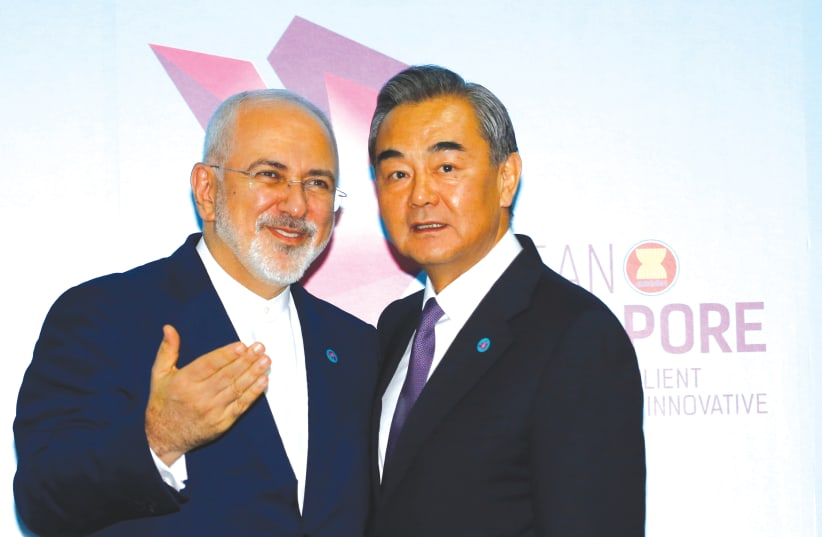 IRAN’S FOREIGN MINISTER Mohammad Javad Zarif and China’s Foreign Minister Wang Yi meet in Singapore in 2018. Energy-hungry China will buy Iranian oil, and in return China will revive Iran’s moribund economy. (photo credit: REUTERS)