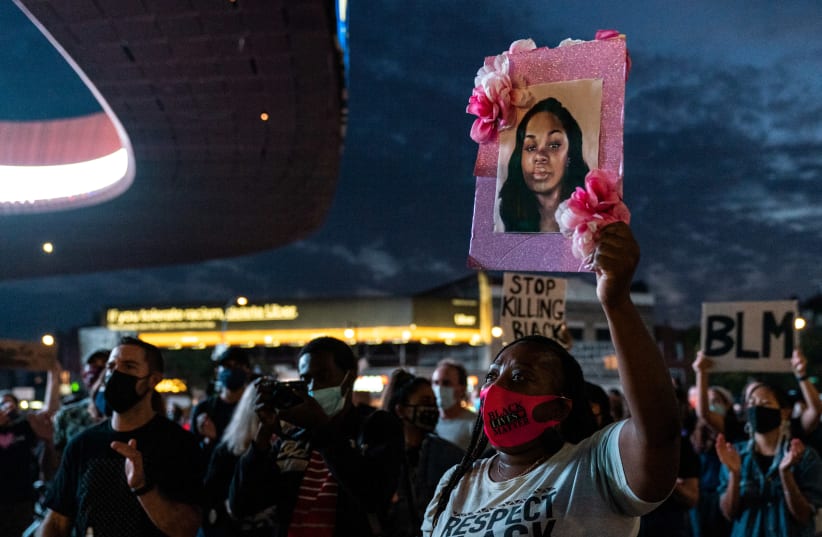 A woman wearing a protective mask holds a portrait of Breonna Taylor during the march for Breonna Taylor in the Brooklyn borough of New York City, New York, U.S., September 25, 2020 (photo credit: REUTERS/JEENAH MOON)