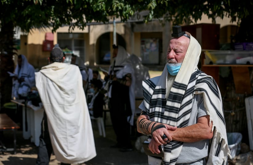 Jewish men pray outside a synagogue in the northern Israeli city of Tzfat, September 23, 2020. (photo credit: DAVID COHEN/FLASH 90)