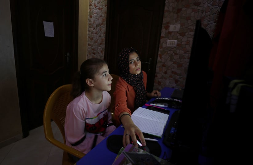 Palestinian sisters Raseel and Mariam Hussein attend their online lessons in their home, amid the coronavirus disease (COVID-19) outbreak, in Gaza City September 22, 2020. (photo credit: MOHAMMED SALEM/ REUTERS)