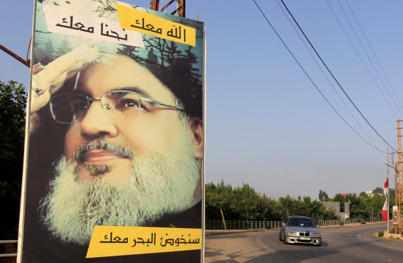 A car drives past a poster depicting Lebanon's Hezbollah leader Sayyed Hassan Nasrallah in Adaisseh village, near the Lebanese-Israeli border, Lebanon July 28, 2020. (photo credit: AZIZ TAHER/REUTERS)