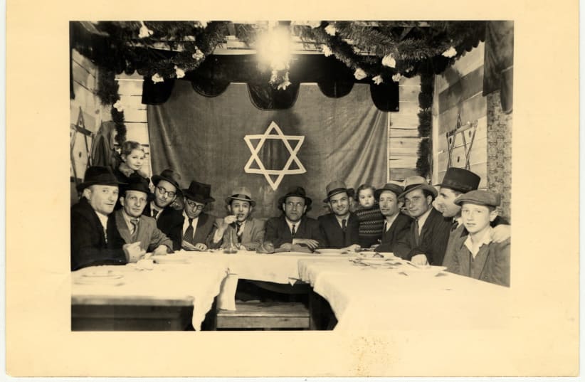 Jewish men gather in a communal sukkah in the Amberg displaced person's camp in Amberg, Germany, October 1947 (photo credit: US HOLOCAUST MEMORIAL MUSEUM/COURTESY OF ABRAHAM MALACH/JTA)