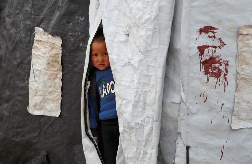 A boy looks out from inside a tent in al-Roj camp, Syria, January 10, 2020. (photo credit: GORAN TOMASEVIC/REUTERS)