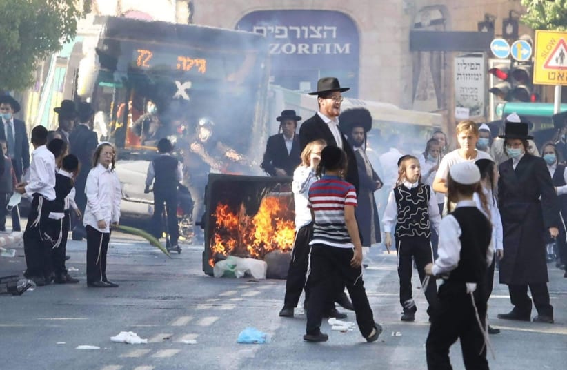 Haredim are seen rioting in Jerusalem and flouting COVID-19 restrictions, with a garbage can lit ablaze to block the street. (photo credit: MARC ISRAEL SELLEM/THE JERUSALEM POST)