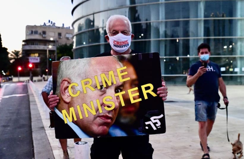 A protester holds a sign that reads, "Crime Minister," during demonstrations held against Prime Minister Benjamin Netanyahu. October, 10, 2020. (photo credit: AVSHALOM SASSONI/ MAARIV)