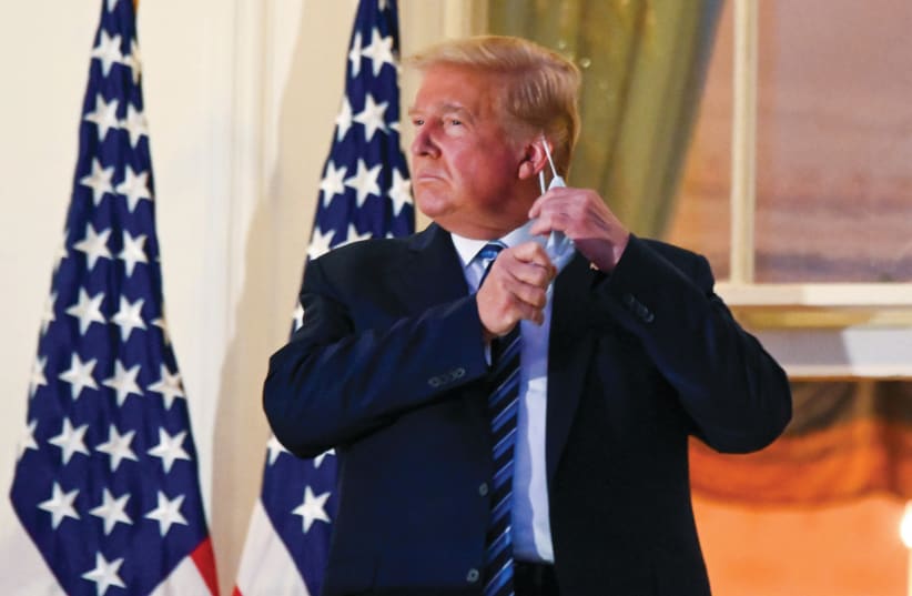US PRESIDENT Donald Trump pulls off his protective face mask after returning to the White House last week, after being hospitalized for the coronavirus. October 9,  2020. (photo credit: REUTERS)