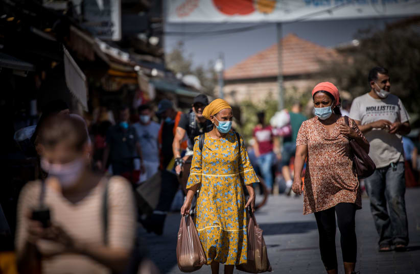 People wearing face masks shop at the Mahane Yehuda Market in Jerusalem on October 7, 2020, during a nationwide lockdown to prevent the spread of COVID-19 (photo credit: YONATHAN SINDEL/FLASH90)