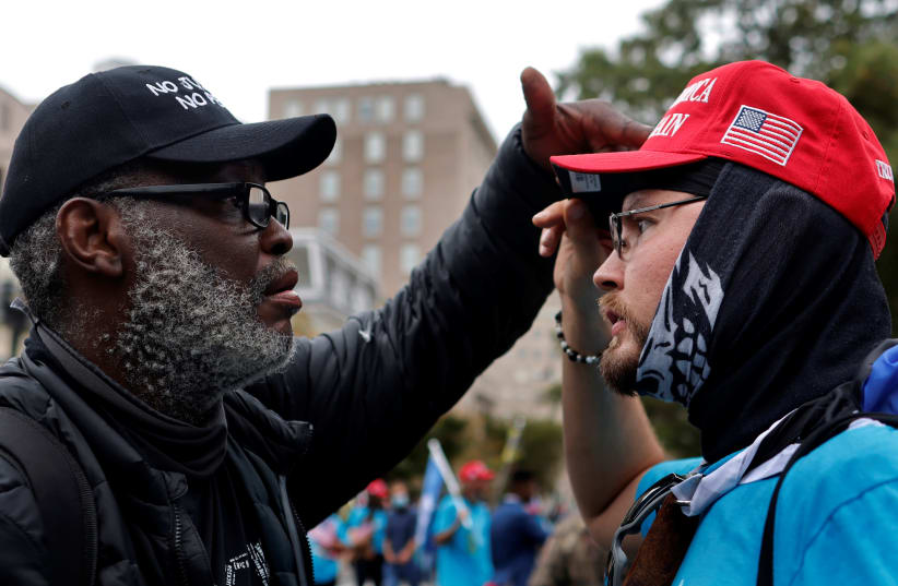 A man and a supporter of U.S. President Donald Trump exchange words during a march around the perimeter of the White House after the President's campaign rally on the South Lawn in Washington, U.S., October 10, 2020. (photo credit: REUTERS/CARLOS BARRIA)