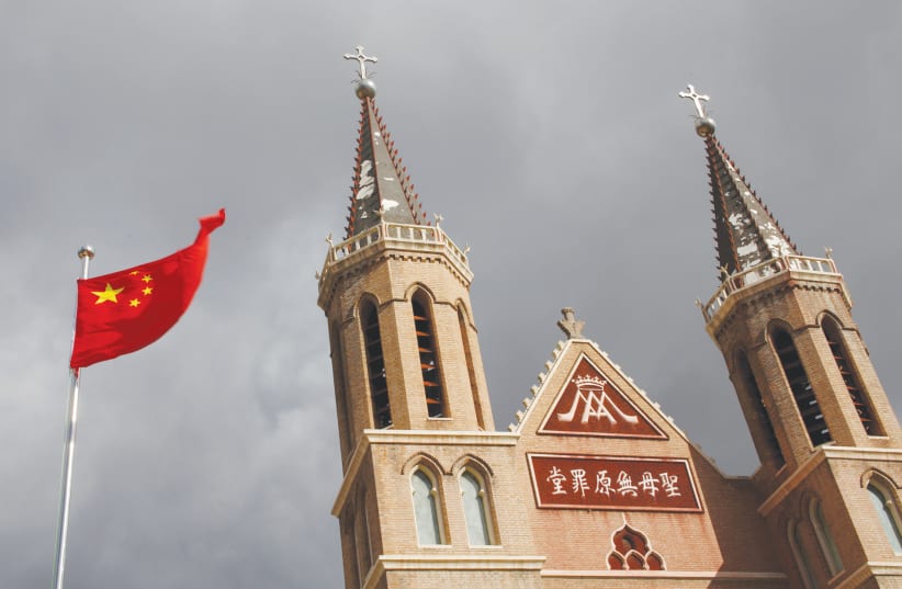 The Chinese flag flies in front of a Catholic church in the village of Huangtugang, China. (photo credit: THOMAS PETER/REUTERS)