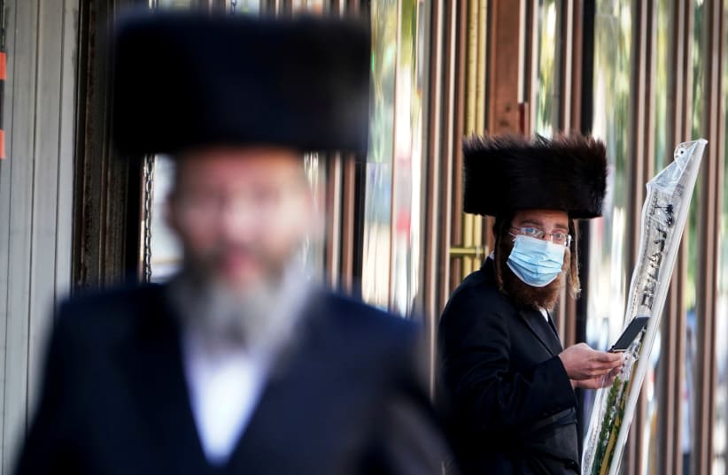 ULTRA-ORTHODOX men – one masked, one not – are seen in the haredi enclave of Borough Park in Brooklyn, New York, on October 6.  (photo credit: CARLO ALLEGRI/REUTERS)