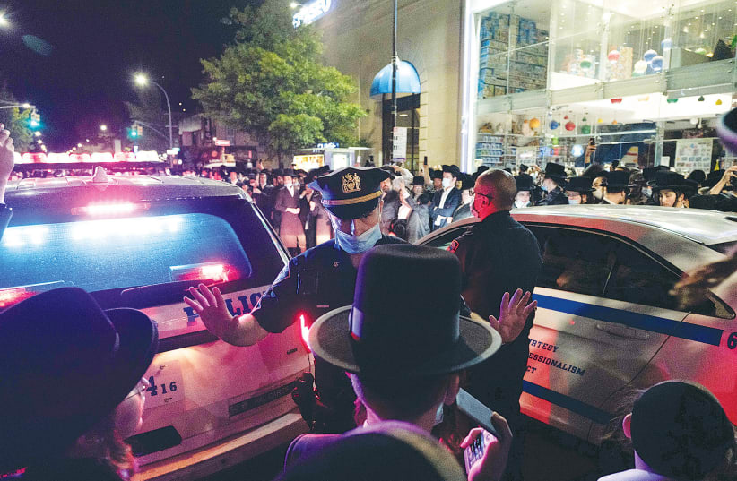 NYPD officers speak with ultra-Orthodox Jews as they protest in the Borough Park neighborhood of Brooklyn, on October 7.  (photo credit: REUTERS)