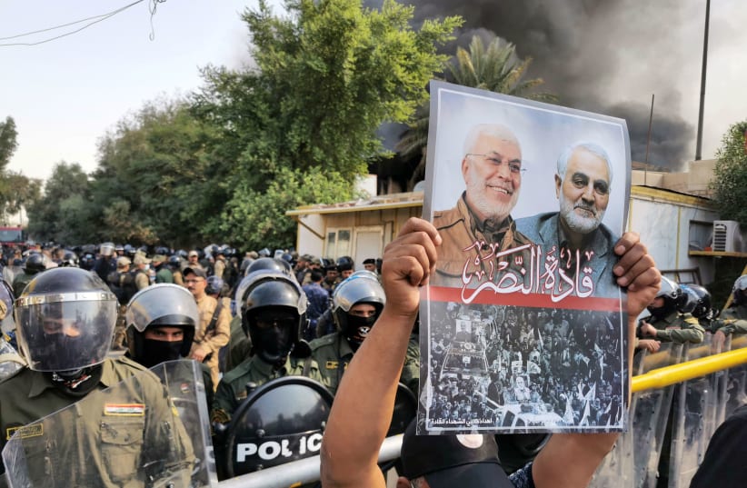 A supporter of Hashid Shaabi holds a picture of late Quds Force commander Qasem Soleimani and Iraqi militia commander Abu Mahdi al-Muhandis during a protest in Baghdad, Iraq, October 17, 2020 (photo credit: REUTERS/THAIER AL-SUDANI)