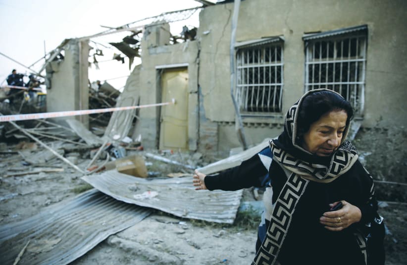 HICRAN QULIYEVA stands in front of her house in Ganja, Azerbaijan, on Saturday, after it was hit by a rocket during the fighting over Nagorno-Karabakh.  (photo credit: REUTERS)