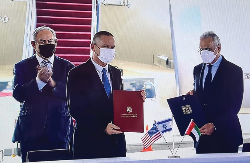 SCIENCE AND TECHNOLOGY Minister Izhar Shay, with Prime Minister Benjamin Netanyahu in the background, holds an agreement on scientific cooperation with his UAE counterpart on Tuesday, at a ceremony at Ben-Gurion Airport held in honor of the first Emirati government delegation to Israel.  One the lef (photo credit: ELAD MALKA)