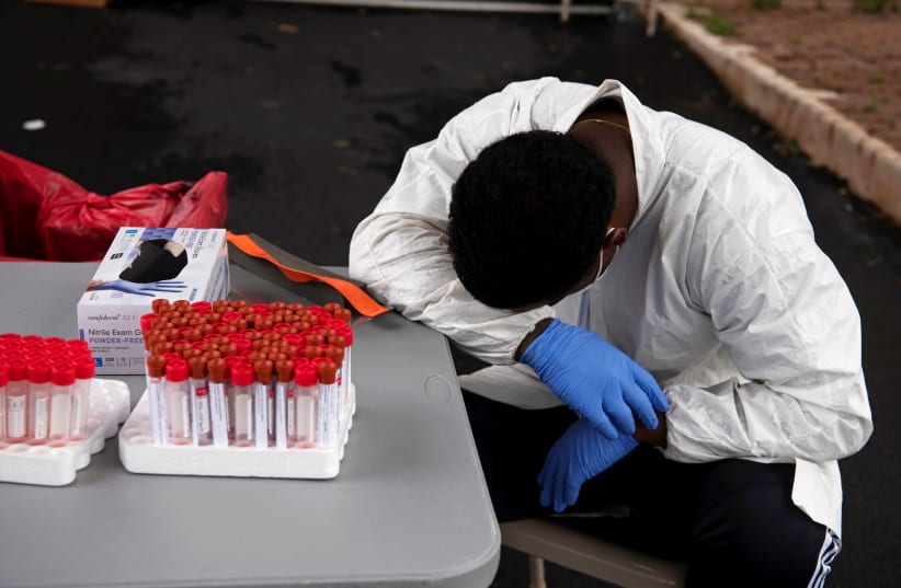 Overheated, a healthcare worker takes a break as people wait in their vehicles in long lines for the coronavirus disease (COVID-19) testing in Houston, Texas, U.S., July 7, 2020 (photo credit: REUTERS/CALLAGHAN O’HARE)