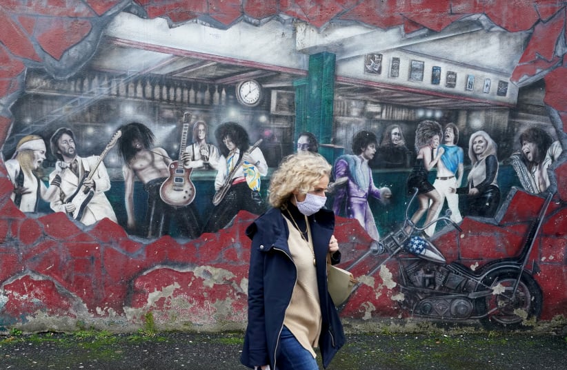 A woman walks past a wall mural during the resurging coronavirus outbreak in Galway, Ireland, October 20, 2020. (photo credit: REUTERS/CLODAGH KILCOYNE)