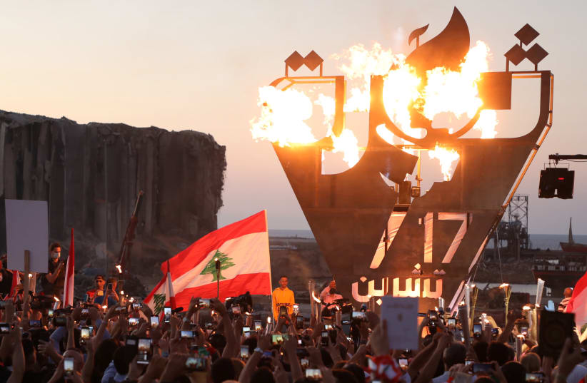 Anti-government demonstrators take pictures of a metal sculpture spelling out "revolution" topped by flames. (photo credit: MOHAMED AZAKIR / REUTERS)