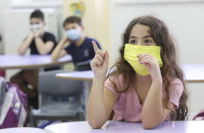 A masked student raises her hand on her first day back in school, November 1, 2020.  (photo credit: MARC ISRAEL SELLEM)