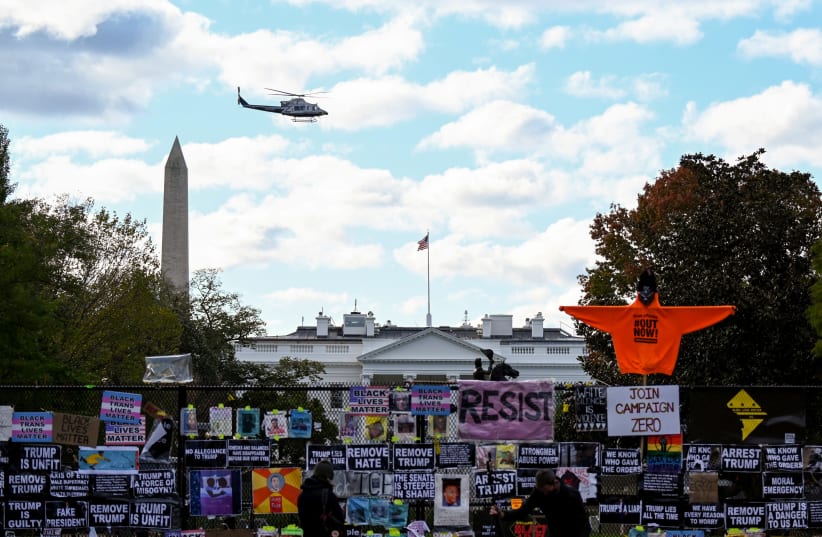 Helicopter passes over the White House, seen behind a fence and protest posters, the day before the U.S. presidential election in Washington, D.C., U.S., November 2, 2020. (photo credit: ERIN SCOTT/REUTERS)