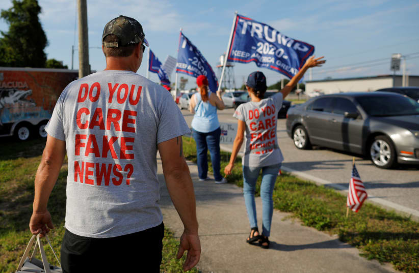 Supporters of US President Donald Trump, wearing t-shirts reading "Do You Care Fake News?" wave to passing drivers during a roadside sign waving rally in the Pinellas County city of Clearwater, Florida, US, May 15, 2019 (photo credit: REUTERS/BRIAN SNYDER)