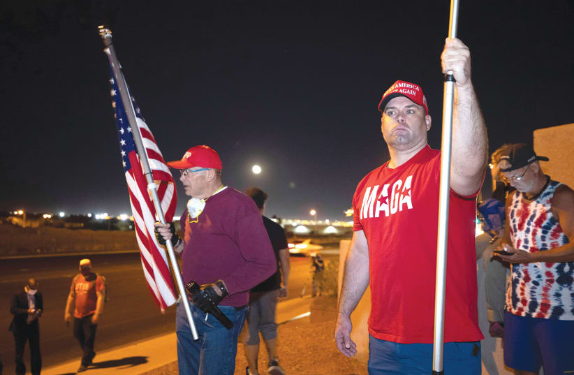 TWO SUPPORTERS of US President Donald Trump hold American flags during a ‘Stop the Steal’ protest in North Las Vegas, Wednesday. (photo credit: STEVE MARCUS/REUTERS)