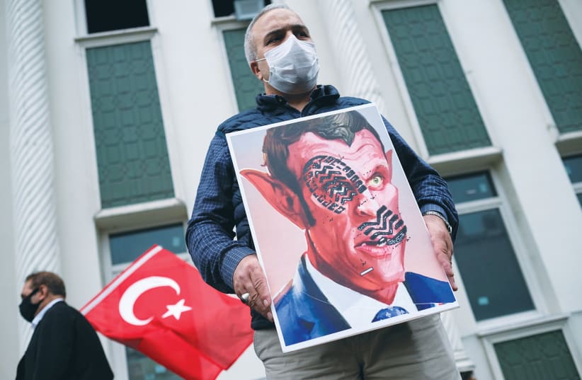 A MAN HOLDS a placard of a defaced picture of  French President Emmanuel Macron during a protest in Istanbul, on October 30, against the publications of a cartoon of Prophet Mohammad and Macron’s comments. (photo credit: MURAD SEZER/REUTERS)
