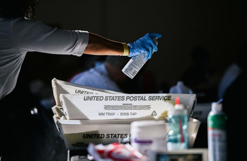 An employee of the Fulton County Board of Registration and Elections disinfects plastic trays while processing ballots in Atlanta, Georgia, US, November 4, 2020.  (photo credit: REUTERS/BRANDON BELL)